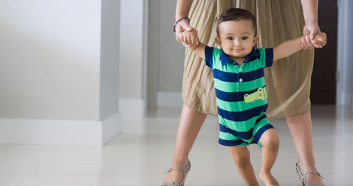 Child taking first steps with parent guardian